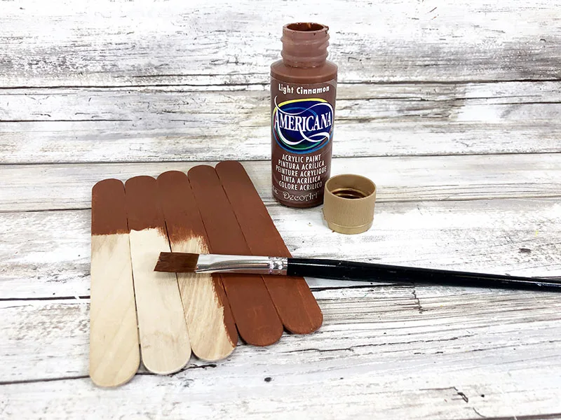 Painting craft sticks brown.