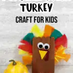 Black text at top says Popsicle Stick Turkey Craft for Kids above completed craft project of turkey made out of popsicle sticks, craft feathers and felt. Turkey sitting next to yellow gourd decoration.