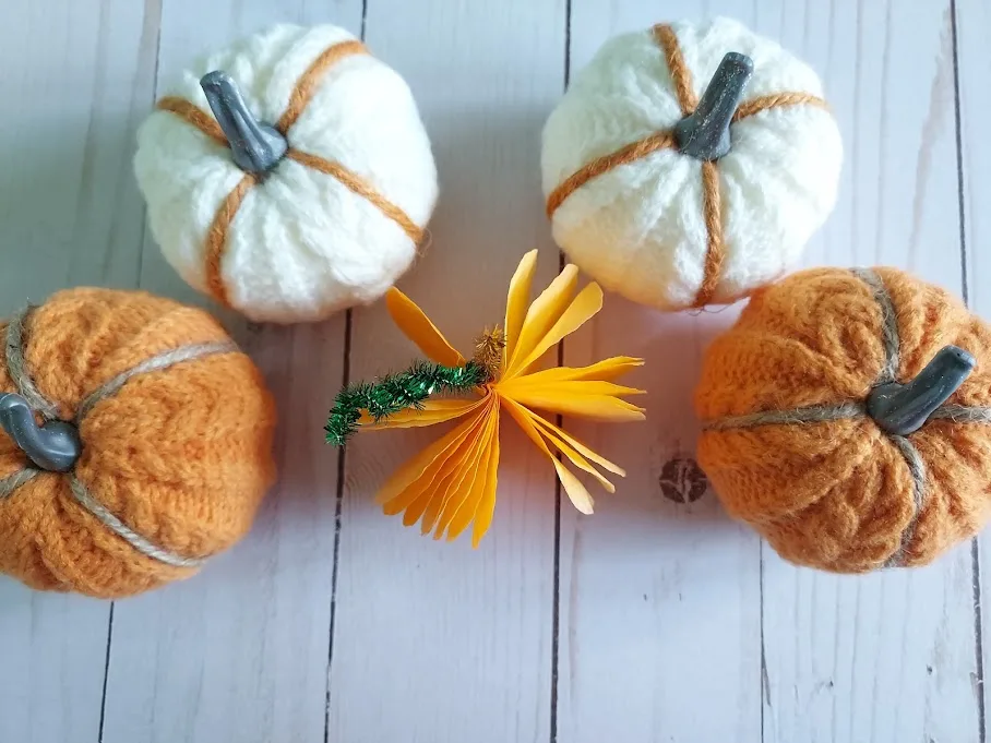 Overhead view of three dimensional coffee filter pumpkin next to other pumpkin decorations.