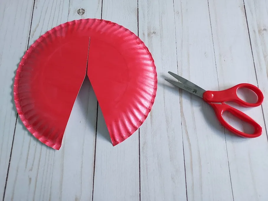 Cutting triangle section out of red painted paper plate to look like ladybug wings.