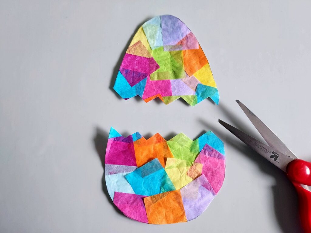 Colorful tissue paper covered egg cut out of template and cut in half with zig zag.