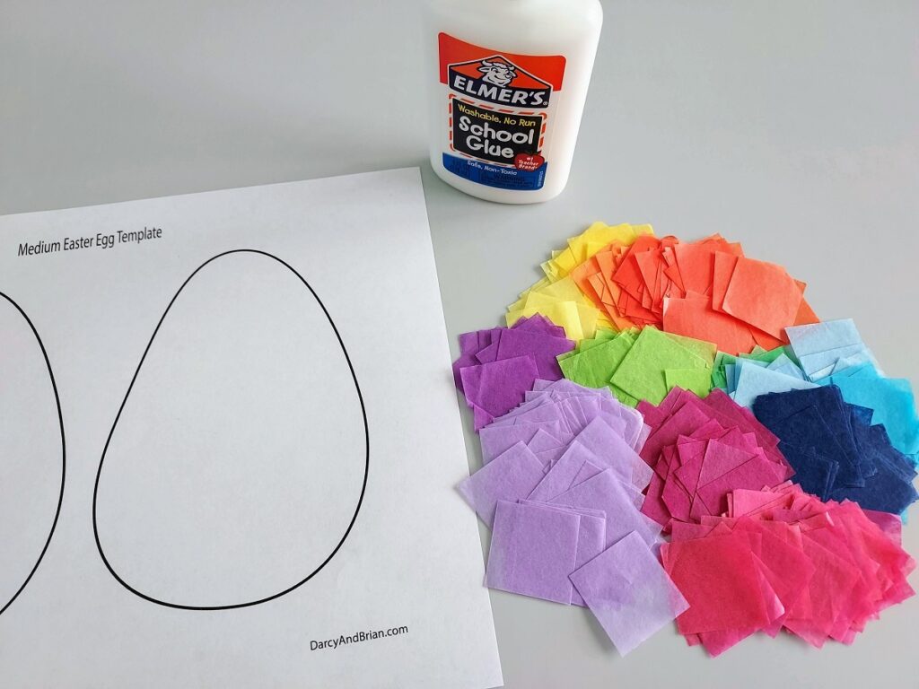 Easter egg printable template laying on table next to tissue paper squares in a variety of colors and a bottle of glue.