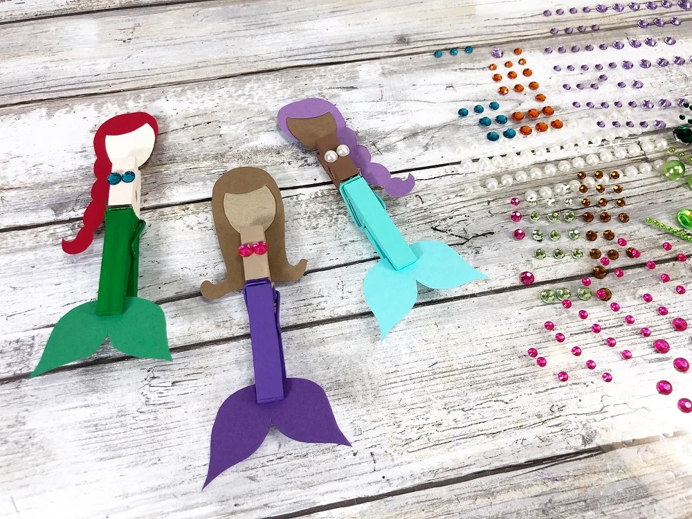 Three different clothespin mermaids painted and assembled with adhesive gems added to create bikini top.