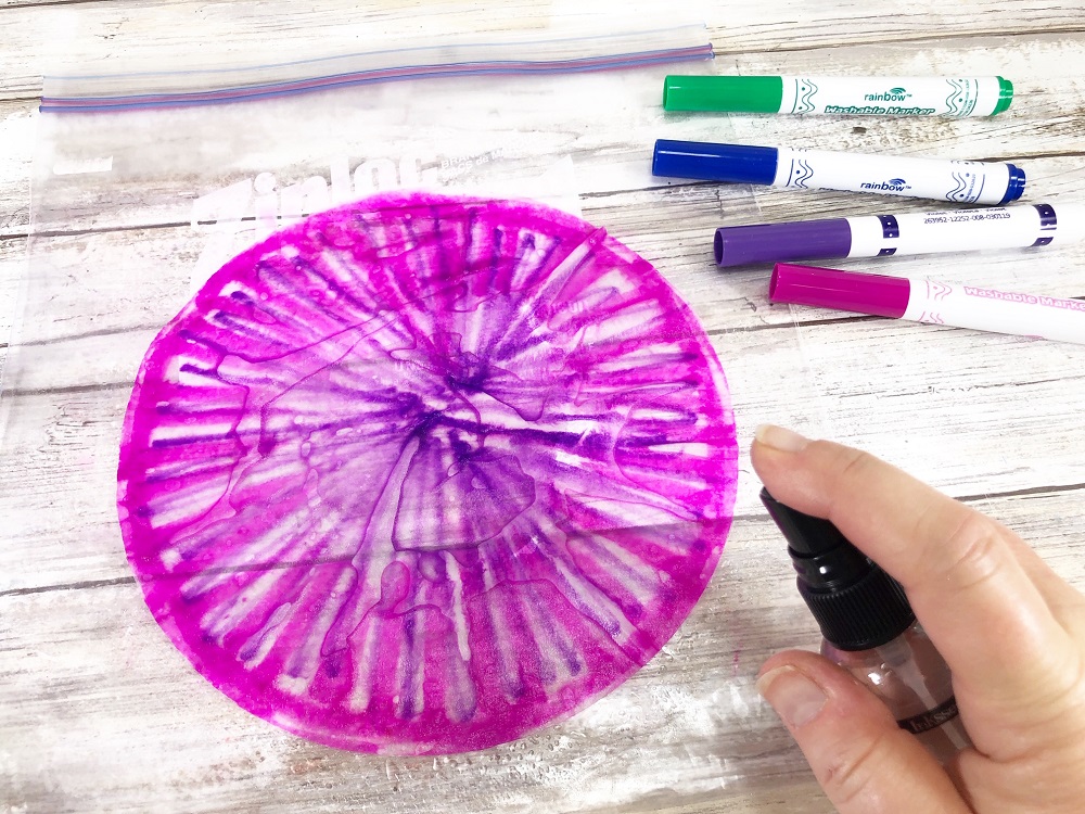 Spraying coffee filter with water to blend the pink and purple colors.