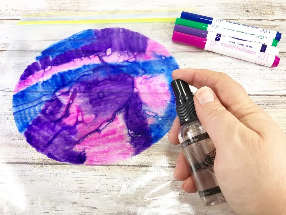 Misting multi-colored coffee filter with water to blend colors similar to tie dye.