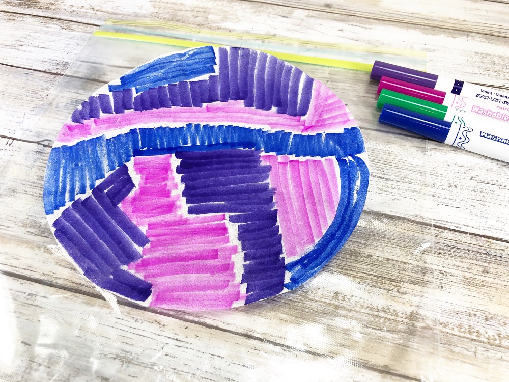 White coffee filter colored in with blue, purple, and pink washable markers.