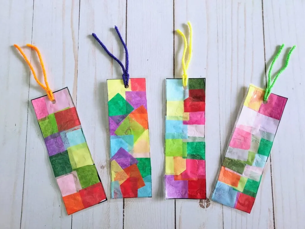 Four laminated tissue paper bookmarks spread out next to each other. Each one has a piece of yarn through the hole near the top.