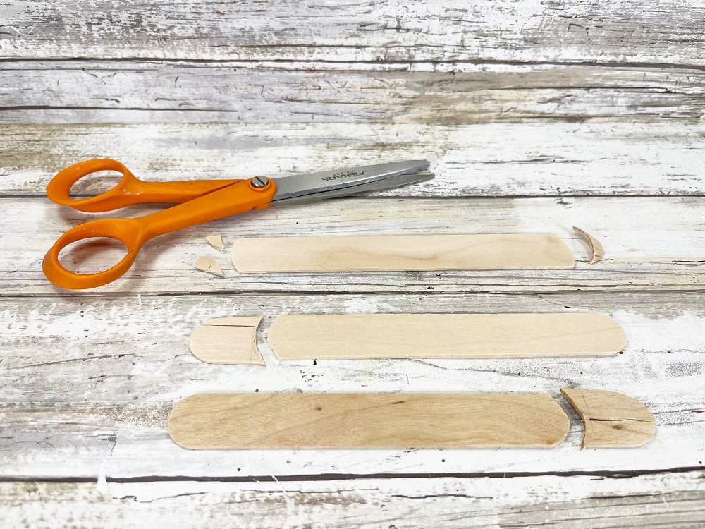 Three craft sticks laying out showing where the ends were cut off with scissors.