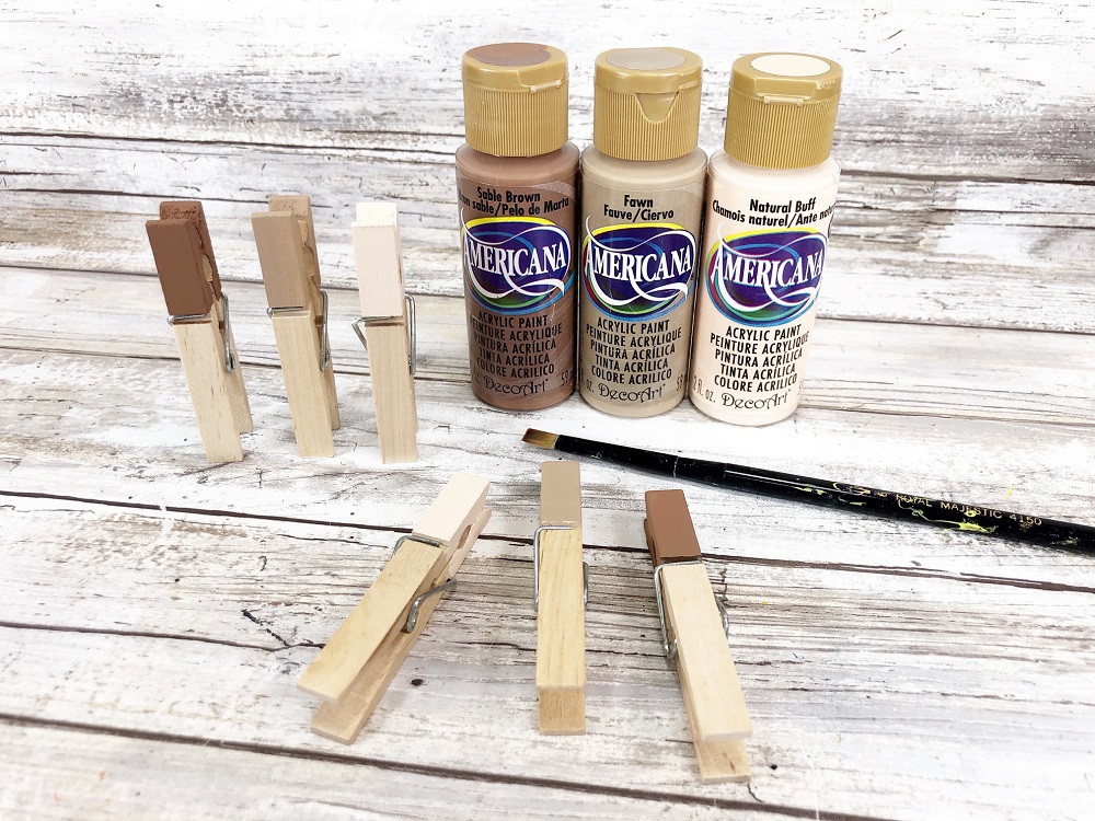 Three bottles of different flesh tone colors. Three clothespins with top part painted standing up and another three laying down drying.