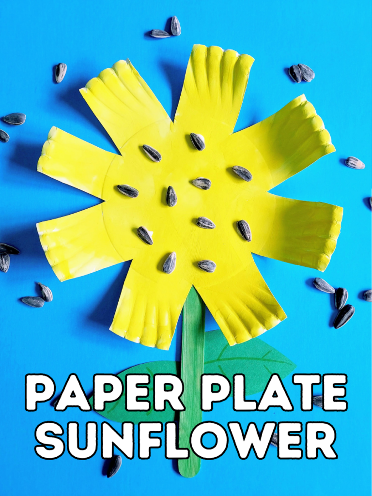 Overhead view of completed craft for kids making a sunflower out of a paper plate and popsicle stick. Yellow paper plate sunflower is laying on blue background with sunflower seeds scattered around it. White text with black outline near bottom says Paper Plate Sunflower.