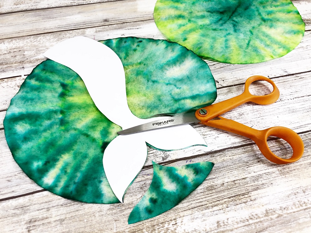 Cutting out mermaid tail shape from green tie dyed coffee filter.
