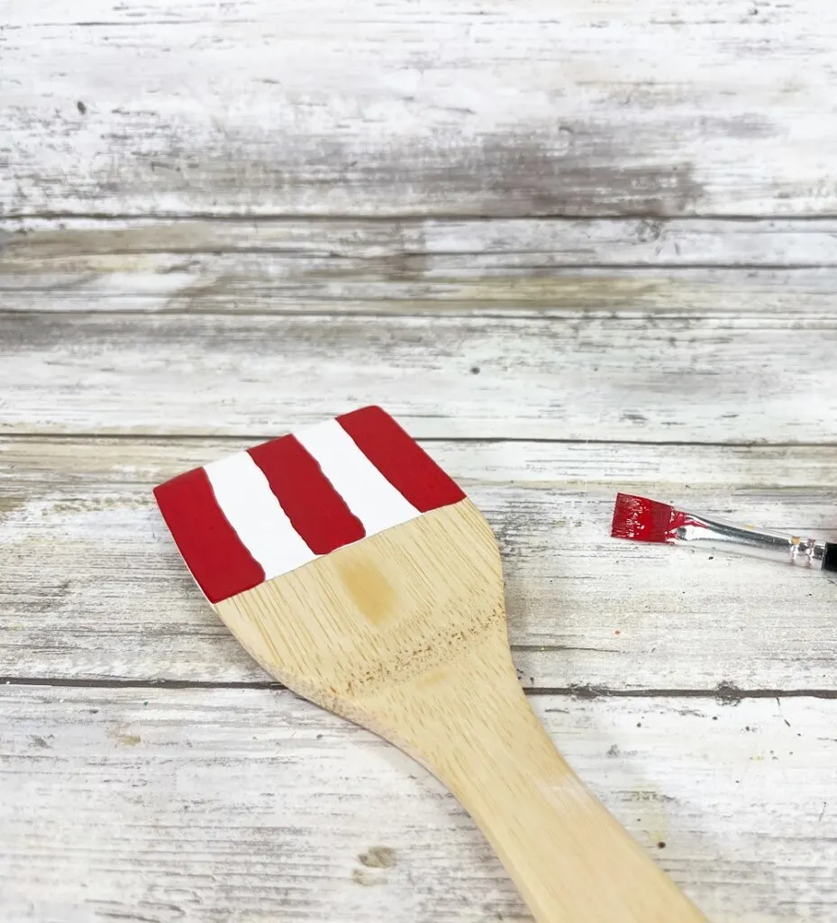 Three red stripes painted over the white on top section of spatula, leaving only two white stripes in the middle.