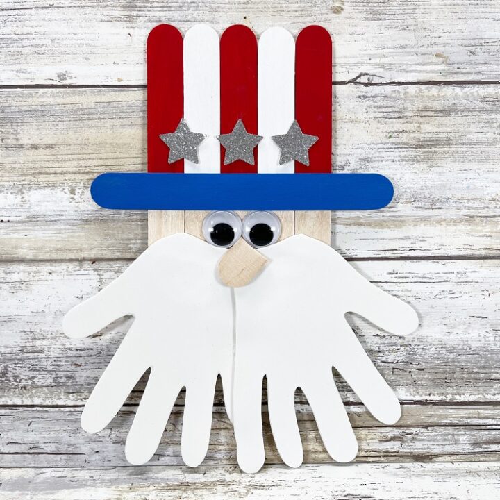 Painted and assembled Popsicle stick Uncle Sam with white handprints for beard.