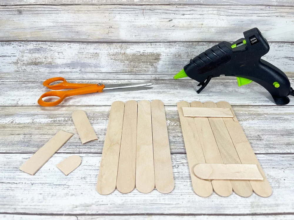 Two sets of four jumbo popsicle craft sticks are lined up together. One set has another stick cut and glued across the top and bottom to keep the four vertical sticks together.