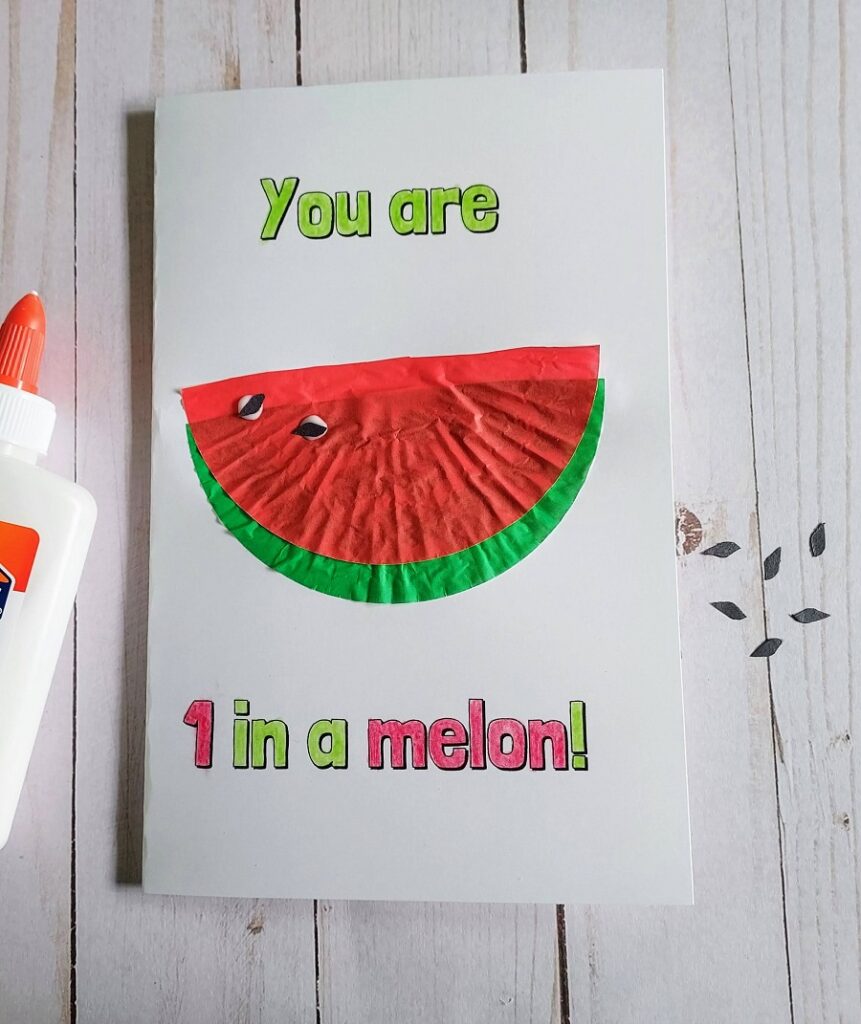 A few small black seeds cut out of construction paper are glued onto the cupcake liner watermelon on the card.