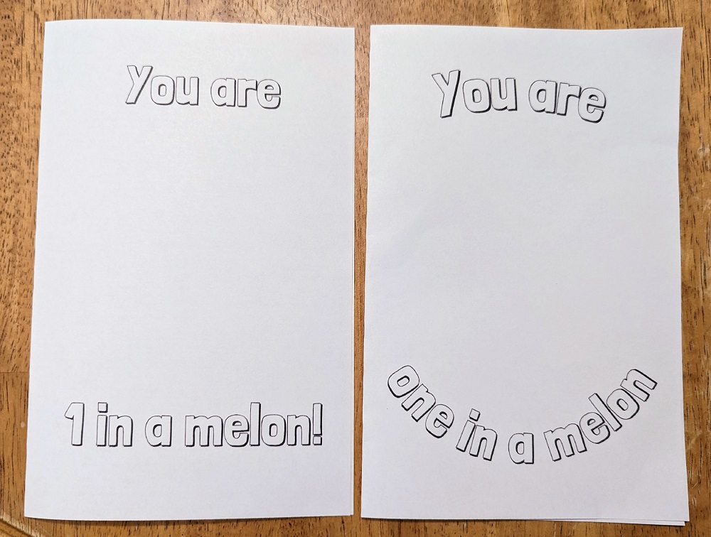 Two cards printed out on white cardstock are folded in half and laying side by side on the table. They both have outlined text for coloring in. Left card says You are 1 in a melon! Right card says You are one in a melon! with text curved.