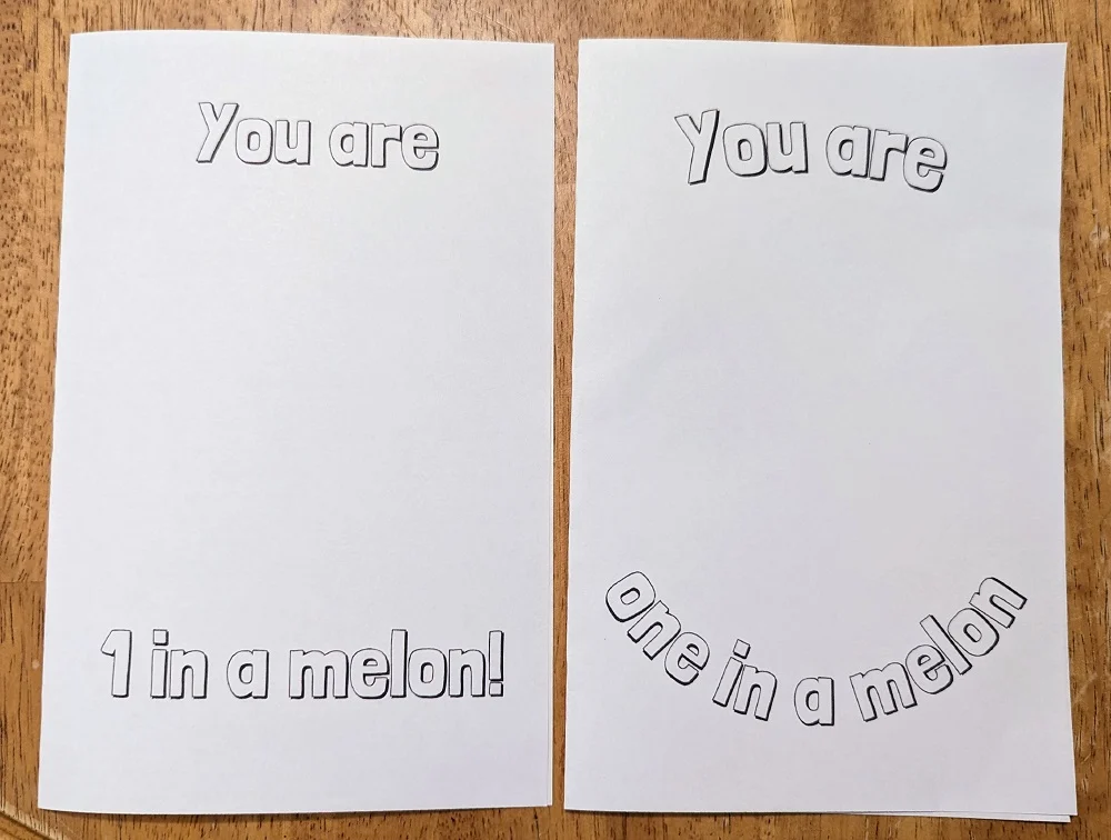 Two cards printed out on white cardstock are folded in half and laying side by side on the table. They both have outlined text for coloring in. Left card says You are 1 in a melon! Right card says You are one in a melon! with text curved.