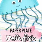 Half of a paper plate painted light blue with googly eyes and a drawn on smile and yarn tied to holes along the flat bottom of plate to look like a jellyfish. Blue yarn tentacles laying over striped scrapbook paper. Text near bottom of photo says Paper Plate Jellyfish.