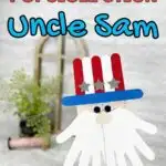 Red and blue text outlined in black at top of photo says Popsicle Stick Uncle Sam. Hand holding up Uncle Sam head made out of popsicle craft sticks and handprint beard.