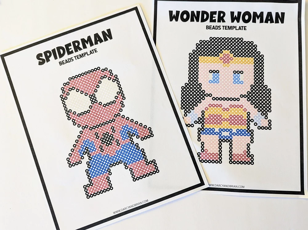 Spiderman and Wonder Woman inspired Perler bead templates printed out and laying next to each other on table.