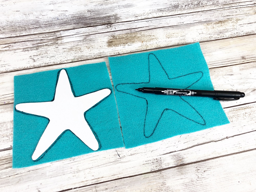 Starfish craft template cut out of white cardstock and traced on turquoise craft felt with black marker.