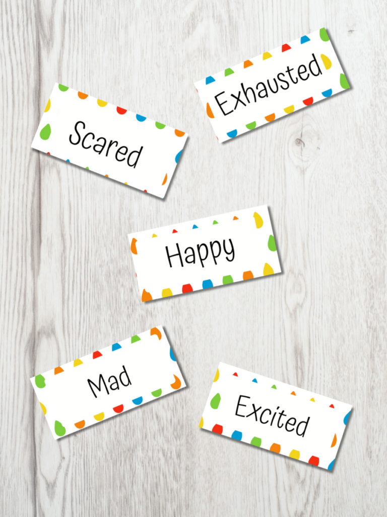 Mockup of five word cards spread out on a white wood table. The cards say scared, exhausted, happy, mad, and excited.