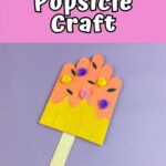 White text outlined with black on a bright pink background at the top of image says Summer Popsicle Craft. Picture shows a popsicle made using craft sticks, paint, and pieces of chenille stems. Popsicle project is laying on purple background.