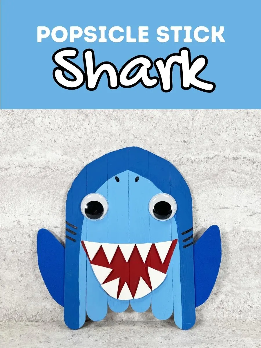 Light blue rectangle at the top of image with white text says Popsicle Stick Shark. Completed project made with painted craft sticks and craft foam.