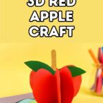 White text with black outline on yellow background says 3D Red Apple Craft. Below text is a picture of an apple craft made out of red paper standing upright with a popsicle stick stem and green leaf. Craft supplies are in the background.