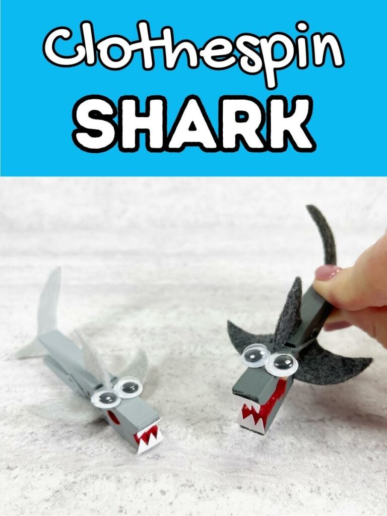 Bright blue box at top with white text outlined in black says Clothespin Shark. Two finished sharks made from painting clothespins and gluing on felt fins, tails, googly eyes and paper teeth. One is painted light gray and one is dark gray and being pinched to open its mouth.