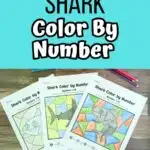 Light aqua blue text box at the top with black and white text that says Shark Color By Number. Three printed out pages that are completely colored in are fanned out on wood table with colored pencils around them.