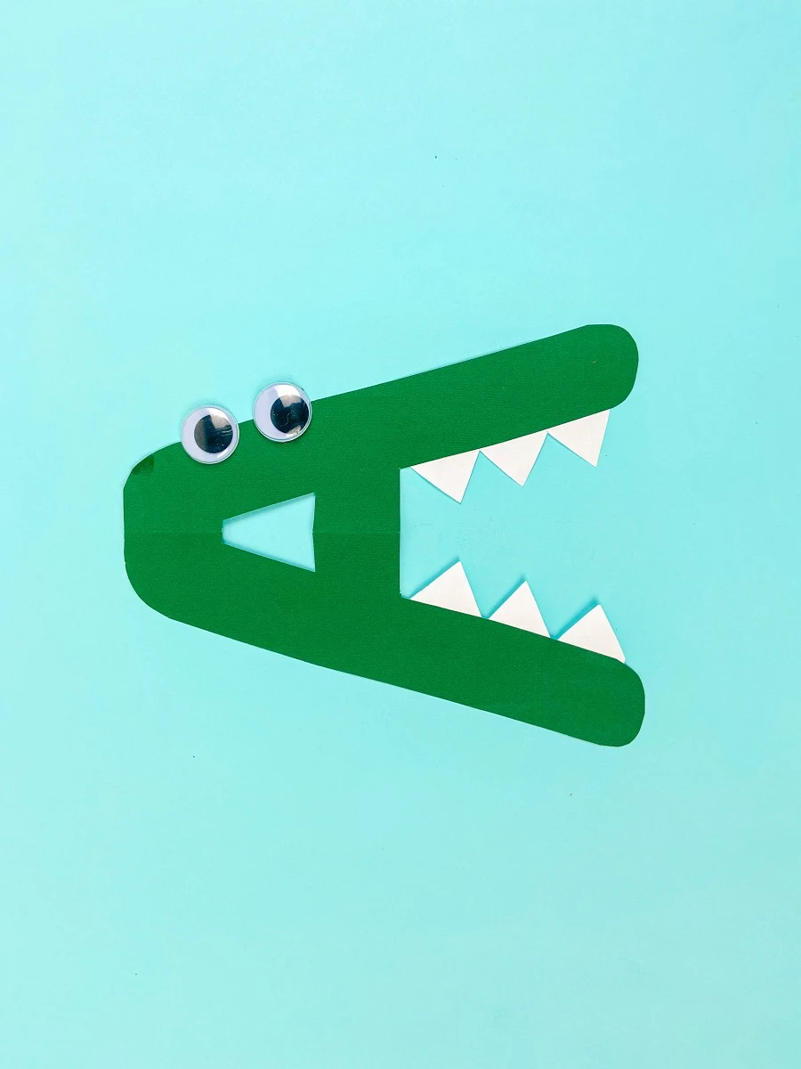 Green letter A with pointy teeth turned on it's side. Googly eyes glued on the top near the point of the A.