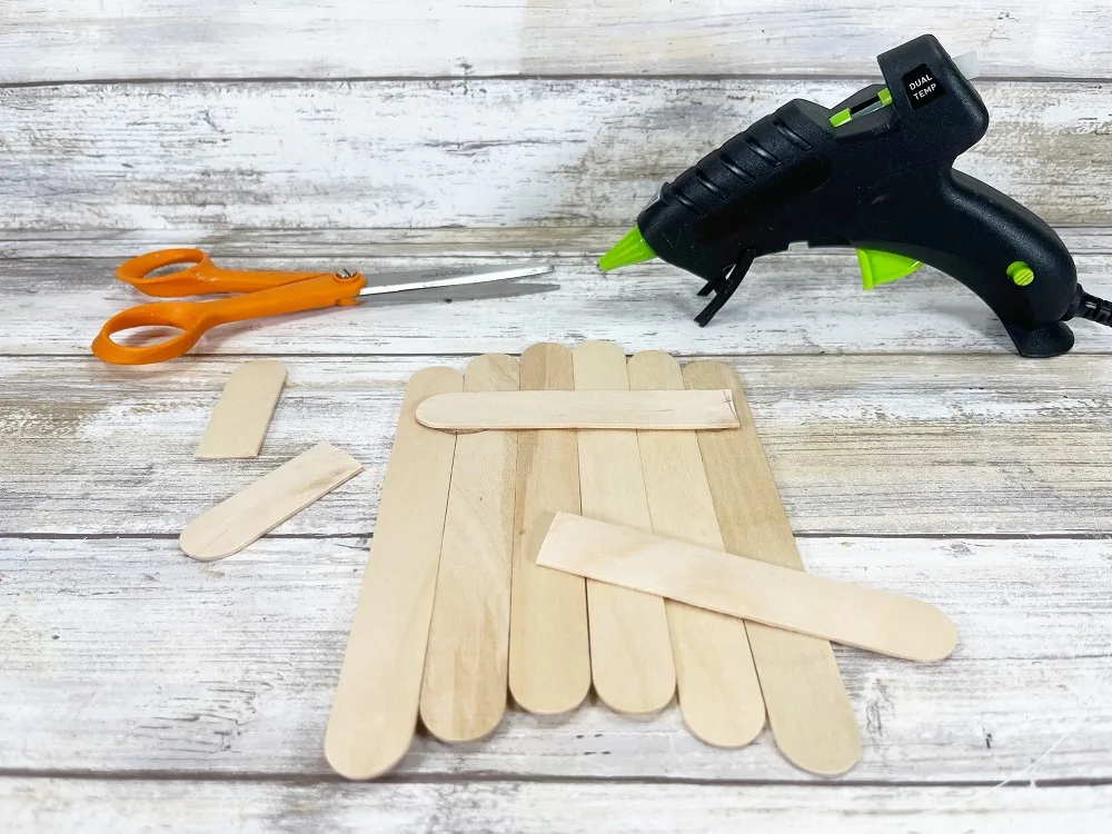 Six jumbo popsicle craft sticks arranged next to each other to create almost an arrow shape. Two more sticks are cut and glued across the back.