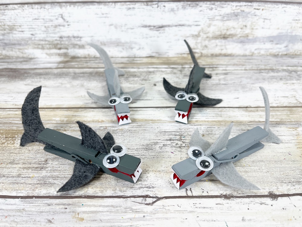 Four completed clothespin sharks painted two different shades of gray.