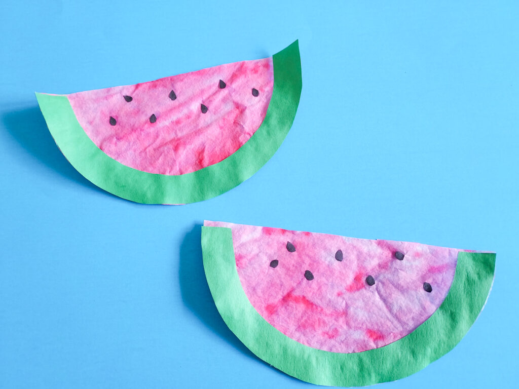 Two coffee filter watermelons finished and laying on a bright blue background.