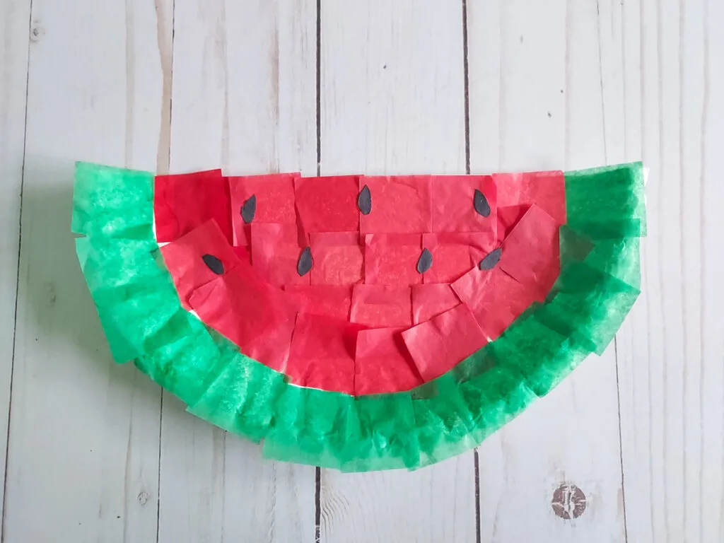 Completed watermelon craft made with tissue paper and half a paper plate.