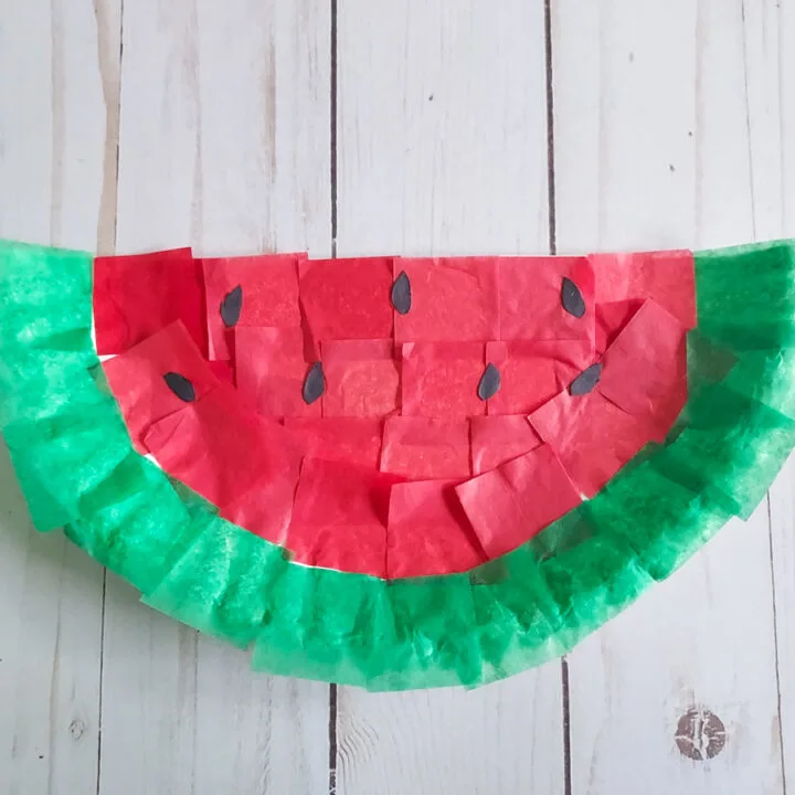 Completed watermelon craft made with tissue paper and half a paper plate.