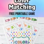 Top part of image has text over a multi-colored background that says Color Matching Free Printable Game. Below is a photo of the printable pages fanned out on a table.