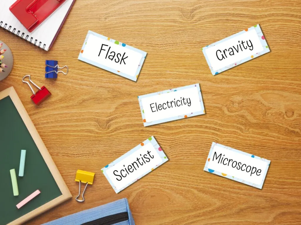 Word card drawing prompts mockup. Five word cards laid out on a school desk along with items like a notebook, small chalkboard, and binder clips.