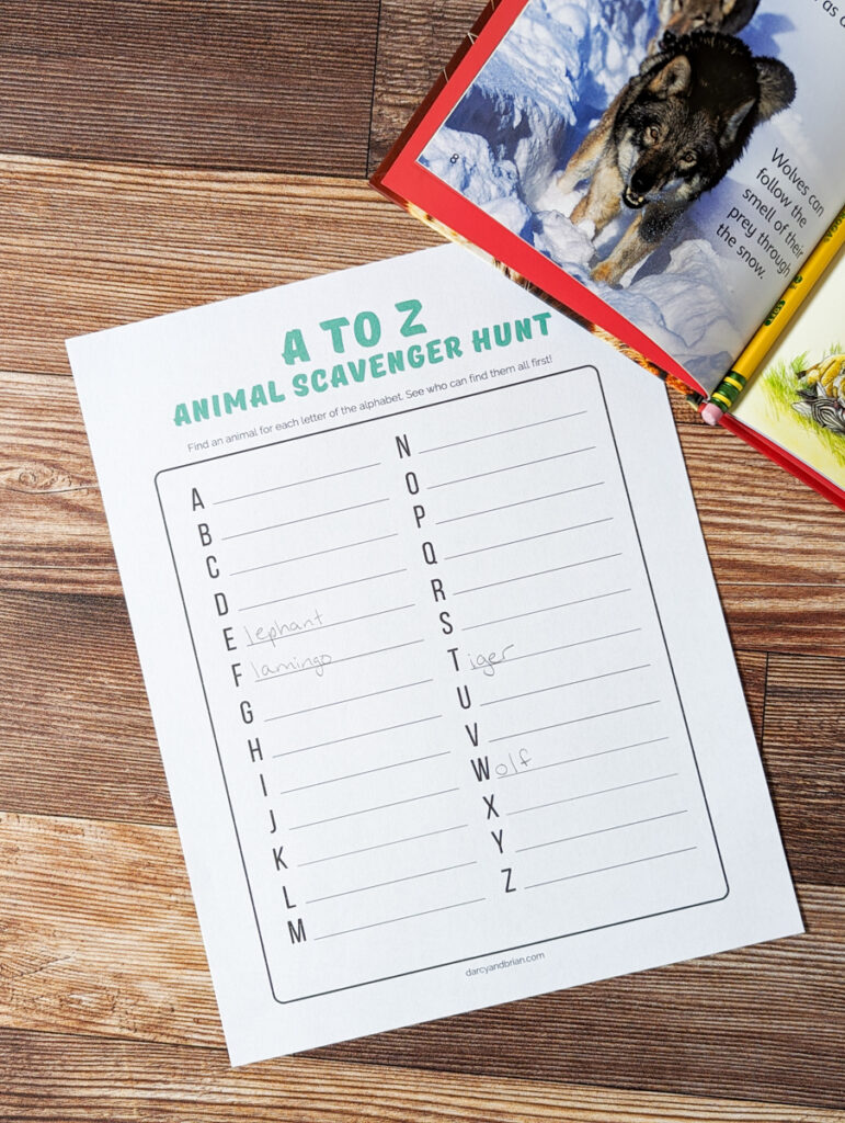 A to Z animal scavenger hunt list page printed out. Book is open to a picture of a wolf and covering the top right corner of worksheet.