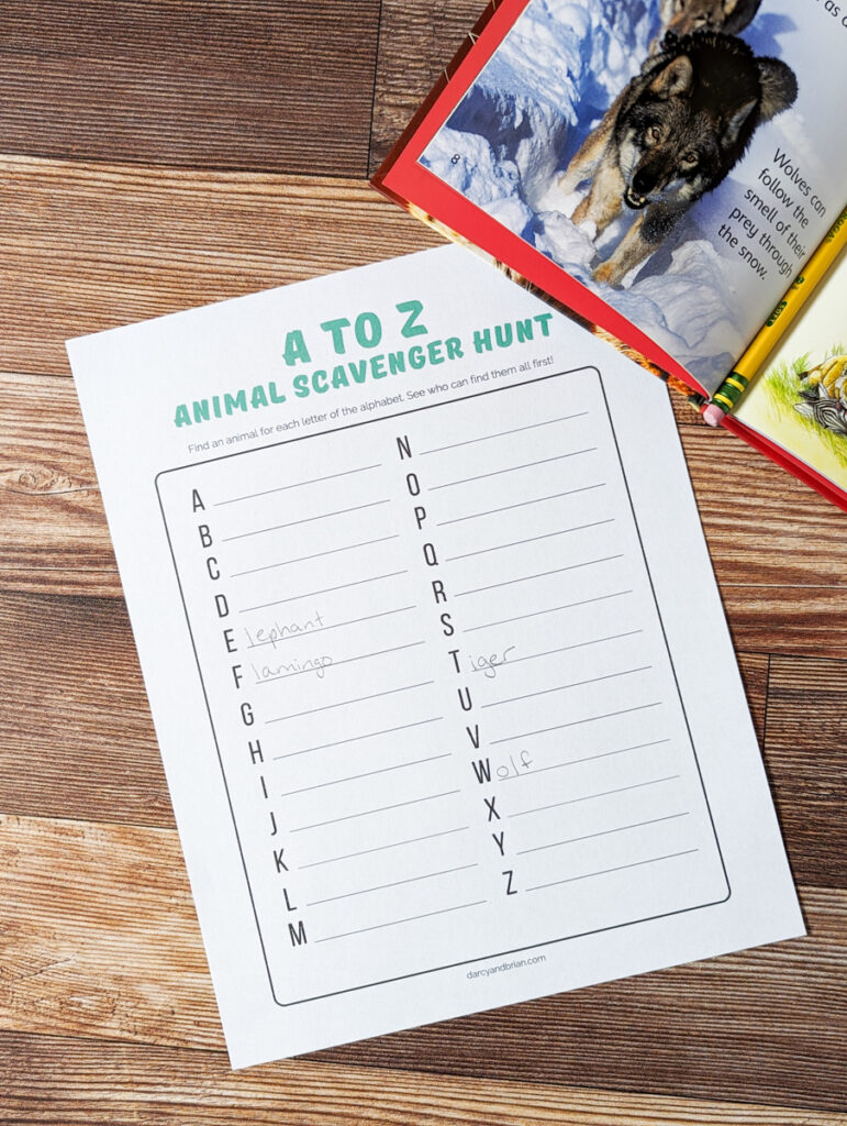 A to Z animal scavenger hunt list page printed out. Book is open to a picture of a wolf and covering the top right corner of worksheet.