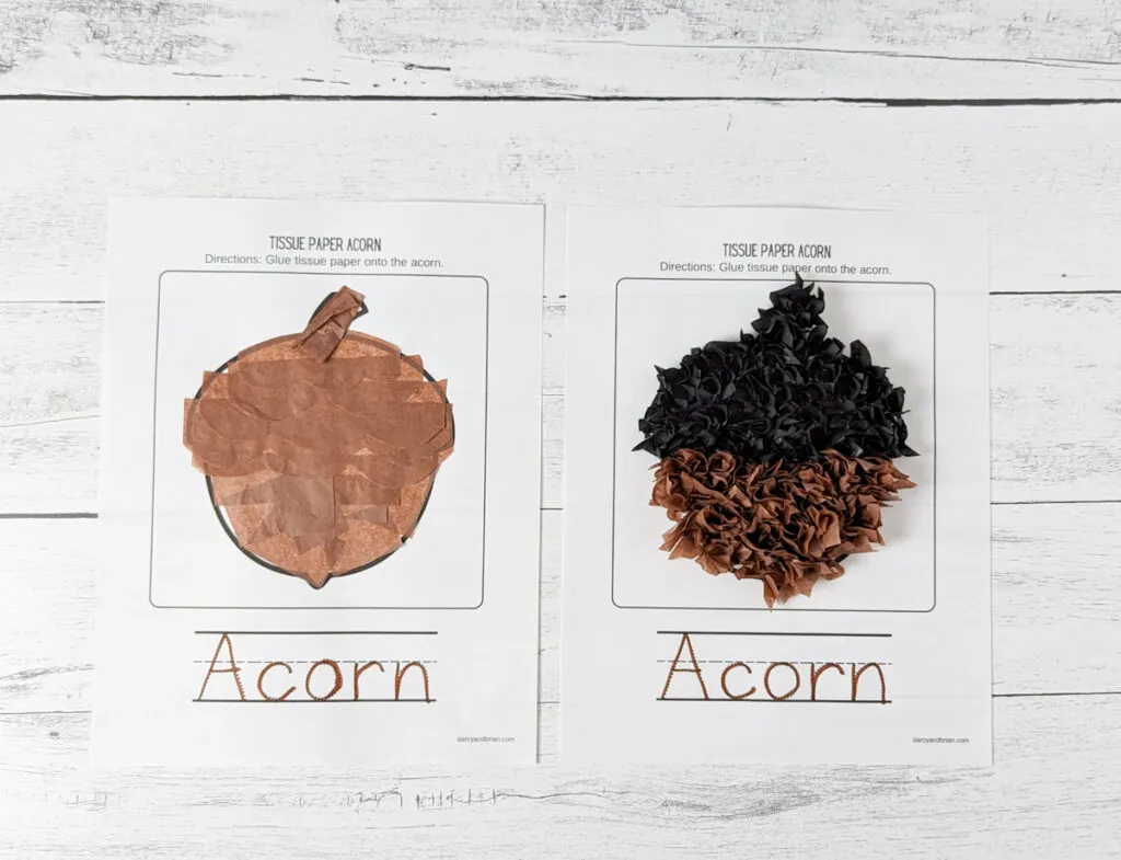 Two acorns made with tissue paper glued on paper lay side by side on a white wood background.