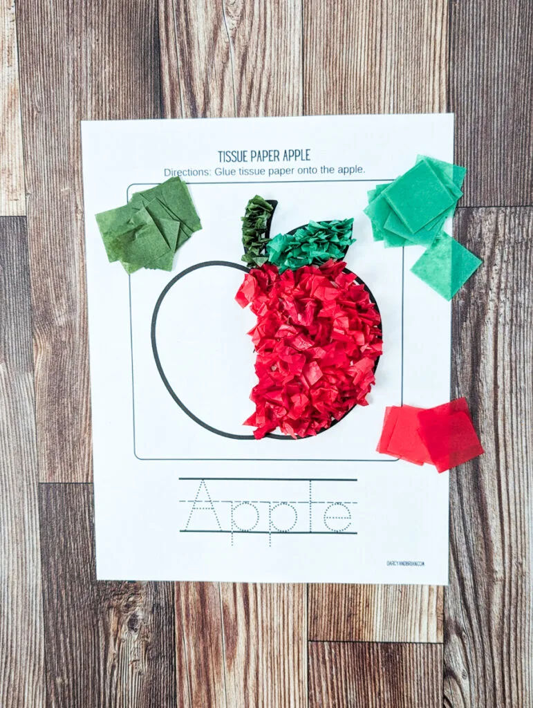 Half of apple template has been covered with red tissue paper.