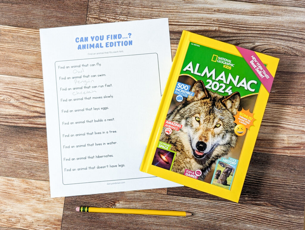 Worksheet with clues about animals for kids to answer laying next to hardcover National Geographic Kids Almanac 2024.