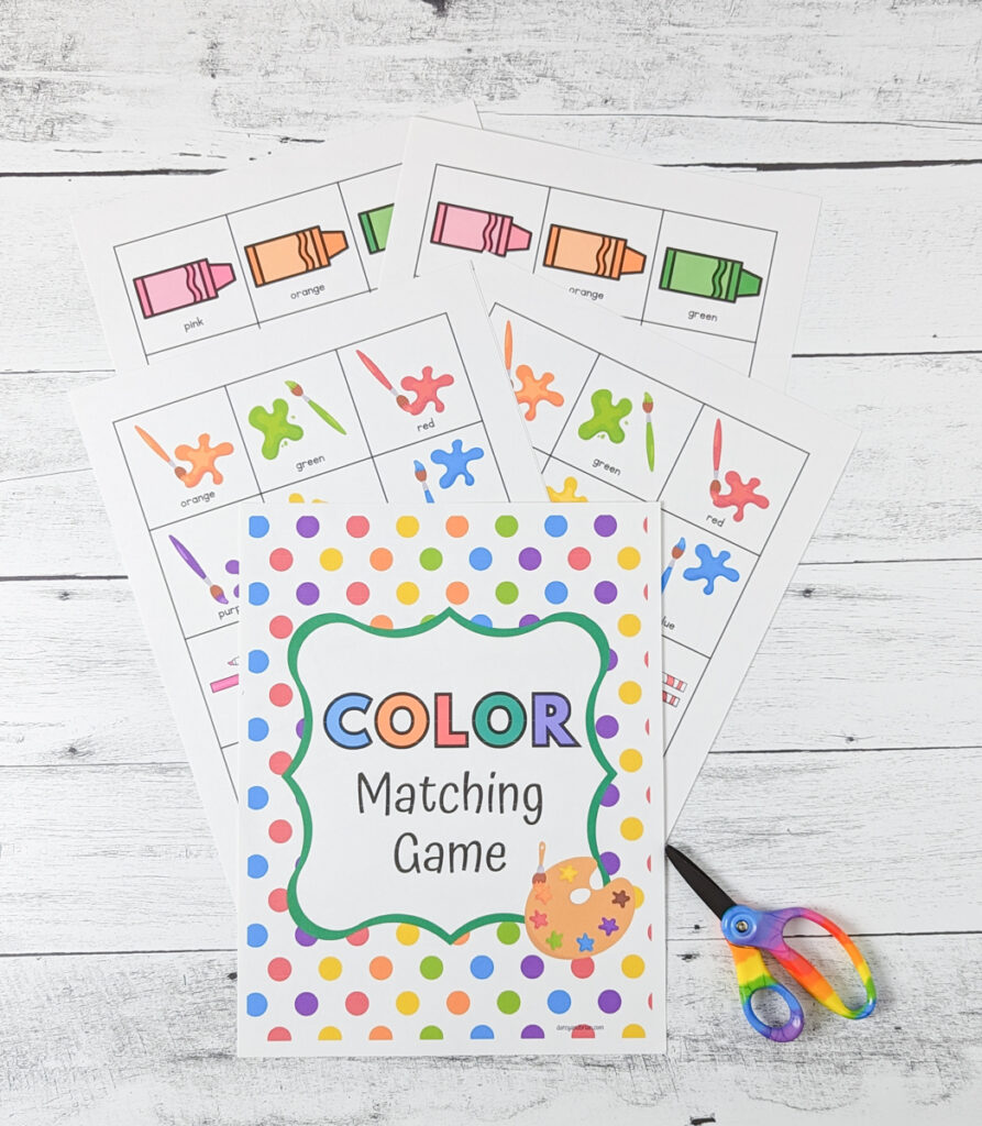 Coloring matching game printable pages laying fanned out on table with a rainbow pair of scissors on the side.