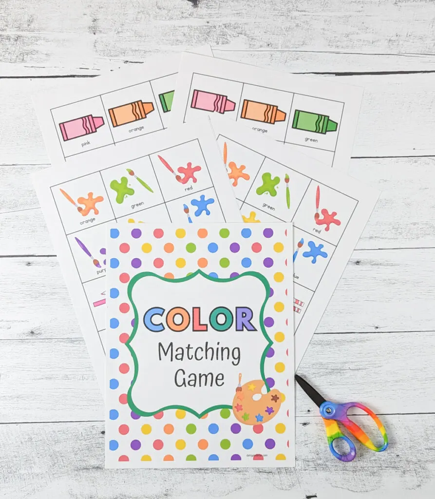 Coloring matching game printable pages laying fanned out on table with a rainbow pair of scissors on the side.