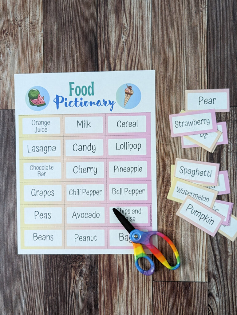 Top down view of printed out Food Pictionary Game. A few cut out word cards lay out on the right side of the full page. A pair of scissors lays over the bottom right corner of the paper.