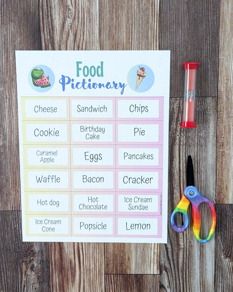 One page of food terms printed out and laying on table next to red sand timer and scissors.