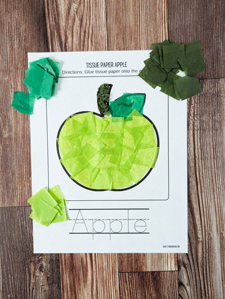 Printable apple craft template covered in light green tissue paper that has been glued down flat, overlapping in places.