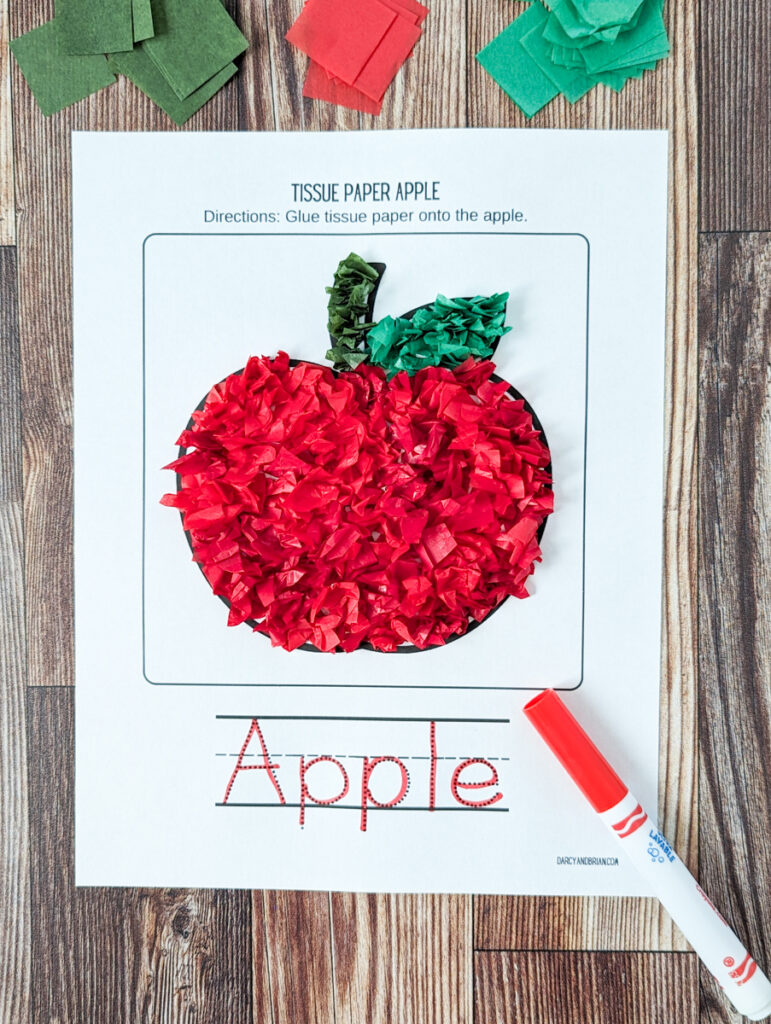 Finished tissue paper apple, covered in red paper. A red marker was used to trace the word "apple" at the bottom. The marker is laying partially over the paper.